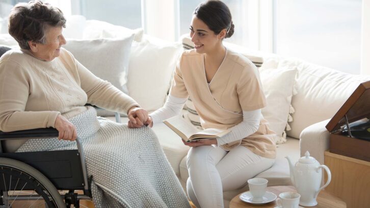 Caregiver reading with woman in wheelchair