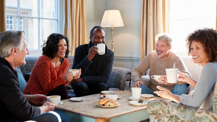 Group Of Middle Aged Friends Meeting Around Table In Coffee Shop