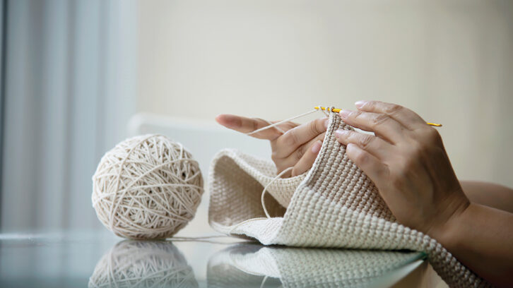 woman crocheting with ball of yarn