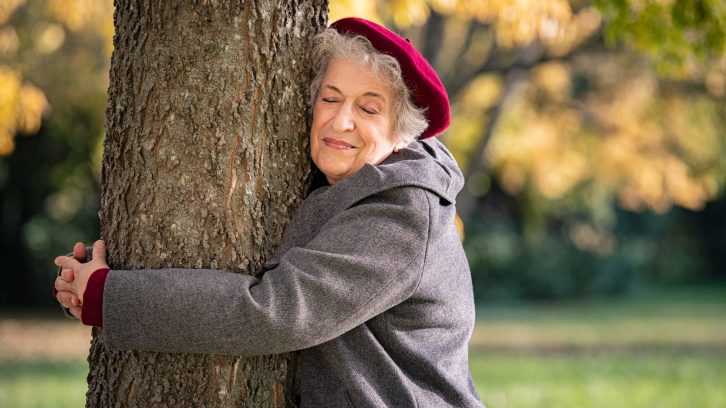 Senior woman hugging a tree