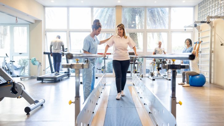 Woman in physical therapy walking on the bars