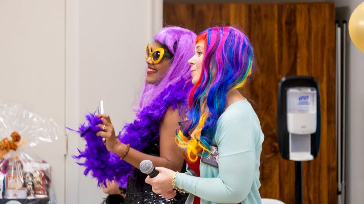 Two smiling women in colorful wigs