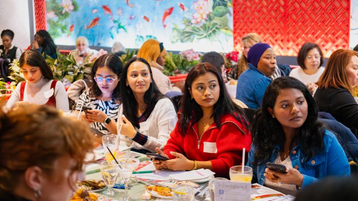 A group of people sitting at a table at the Mosaic Teams Holiday Celebration