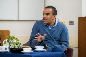 Person in a blue sweater sitting at a tea table