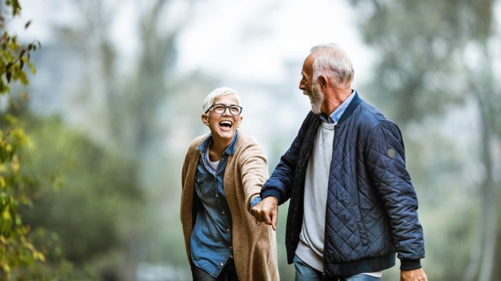 Senior couple walking holding hands and laughing
